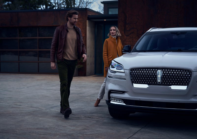 A man and a woman approaching a 2024 Lincoln Aviator® SUV, which illuminates certain lights when they are close | Parks Lincoln of Tampa in Tampa FL