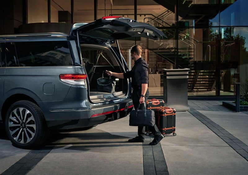 A valet is unloading luggage from the rear cargo area of a 2023 Lincoln Navigator SUV. | Parks Lincoln of Tampa in Tampa FL