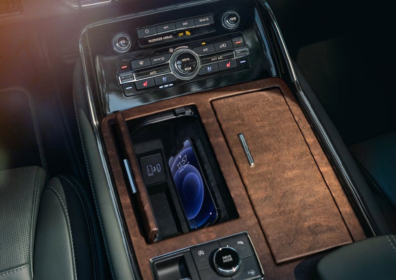 A smartphone is charging on the wireless charging pad* in the front center console cubby. | Parks Lincoln of Tampa in Tampa FL