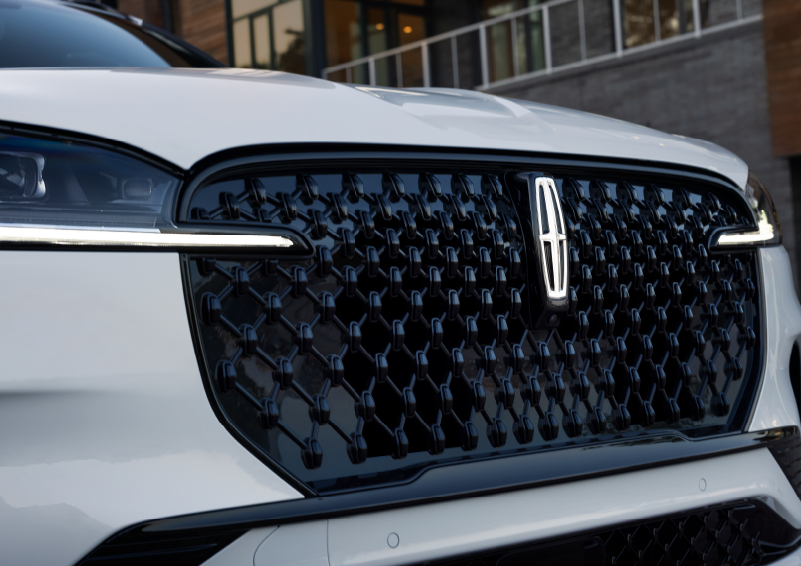 The black grille of a white 2025 Lincoln Aviator® SUV is shown with its fog lights on. | Parks Lincoln of Tampa in Tampa FL