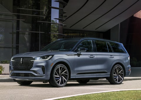 A gray 2025 Lincoln Aviator® SUV is parked outside a modern building showcasing the driver’s side of the vehicle. | Parks Lincoln of Tampa in Tampa FL