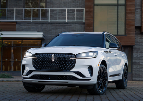 A white 2025 Lincoln Aviator® SUV is shown parked outside a modern building with gray brick and wood accents. | Parks Lincoln of Tampa in Tampa FL