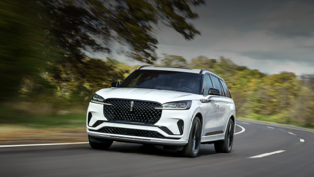A white 2025 Lincoln Aviator® SUV is being driven down a road lined with trees. | Parks Lincoln of Tampa in Tampa FL