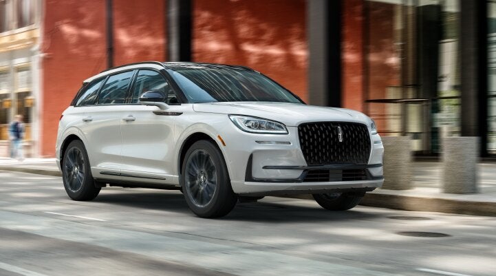 A white 2025 Lincoln Corsair® SUV with the Jet Appearance Package is being driven through a city.| Parks Lincoln of Tampa in Tampa FL