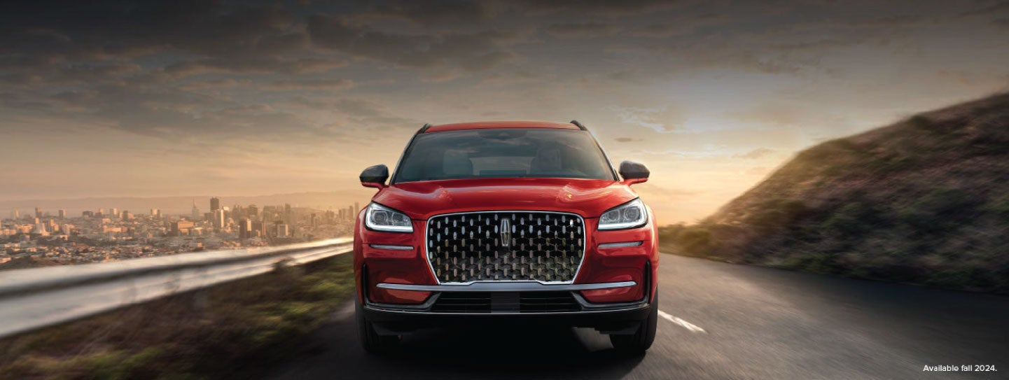 A 2025 red Lincoln Corsair® SUV is being driven down a road at sunset. | Parks Lincoln of Tampa in Tampa FL
