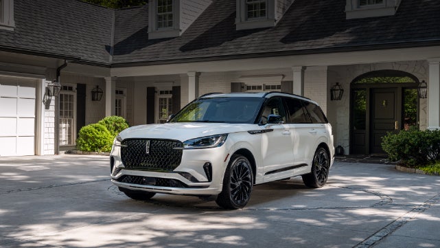 A white 2026 Lincoln Aviator® SUV is parked in the driveway of a luxury home. | Parks Lincoln of Tampa in Tampa FL