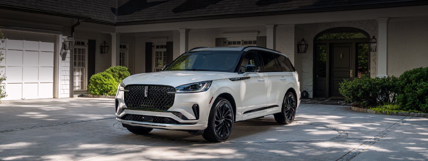 A white 2026 Lincoln Aviator® SUV is parked in the driveway of a luxury home. | Parks Lincoln of Tampa in Tampa FL