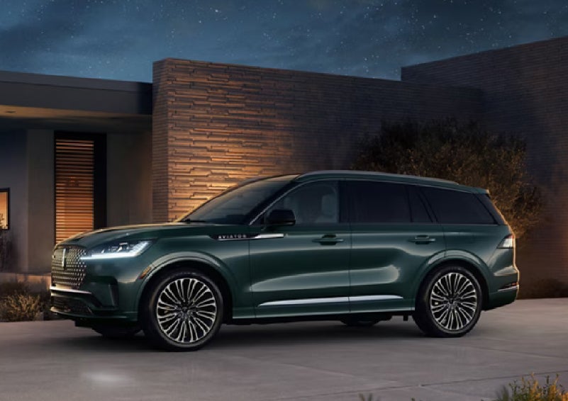 A green 2027 Lincoln Aviator® SUV is parked outside a contemporary home. | Parks Lincoln of Tampa in Tampa FL