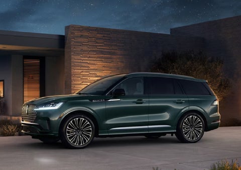 A green 2027 Lincoln Aviator® SUV is parked outside a contemporary home. | Parks Lincoln of Tampa in Tampa FL