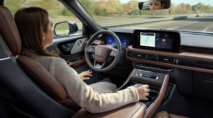 A 2027 Lincoln Aviator® SUV is being driven hands-free on a highway lined with trees. | Parks Lincoln of Tampa in Tampa FL