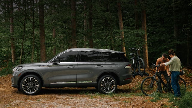 A father and son load e-bikes on a bike rack attached to a 2027 Lincoln Aviator® SUV. | Parks Lincoln of Tampa in Tampa FL