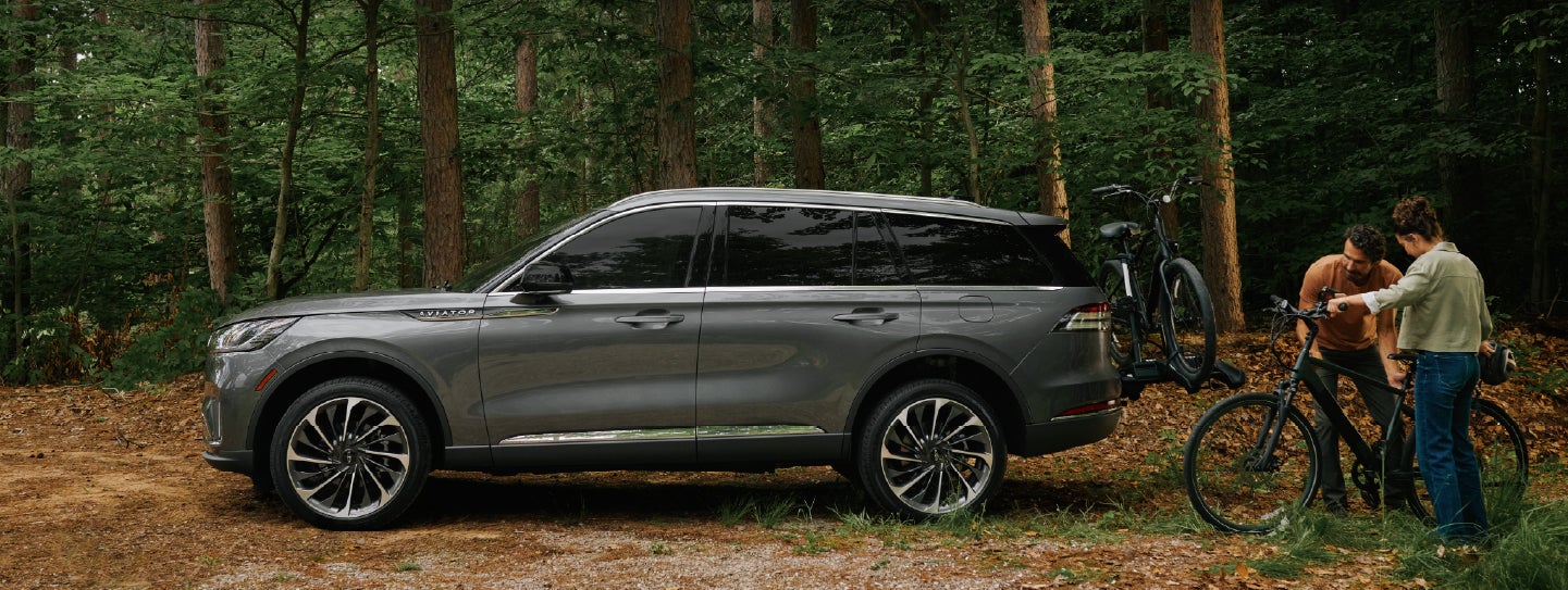 A father and son load e-bikes on a bike rack attached to a 2027 Lincoln Aviator® SUV. | Parks Lincoln of Tampa in Tampa FL